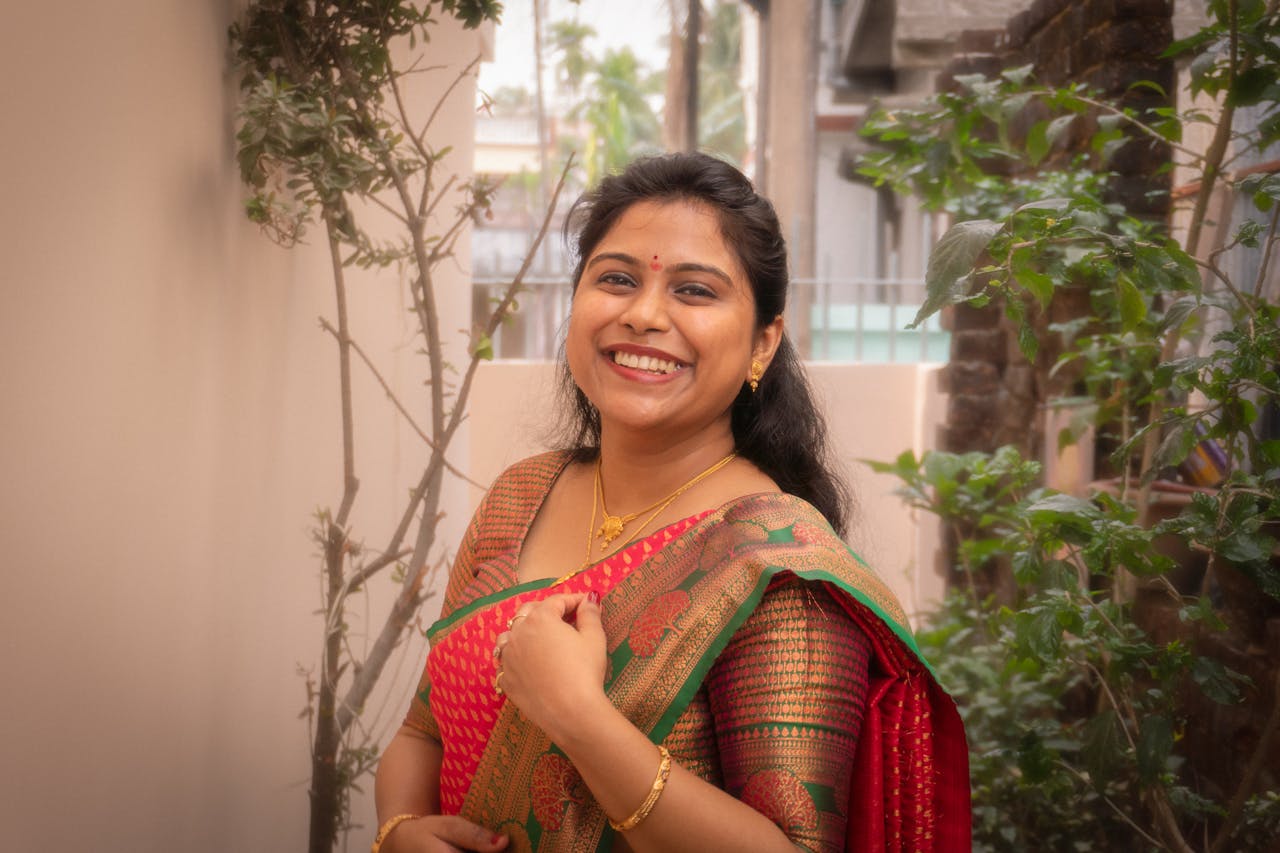 A joyful woman in a colorful saree posing outdoors, capturing cultural elegance.